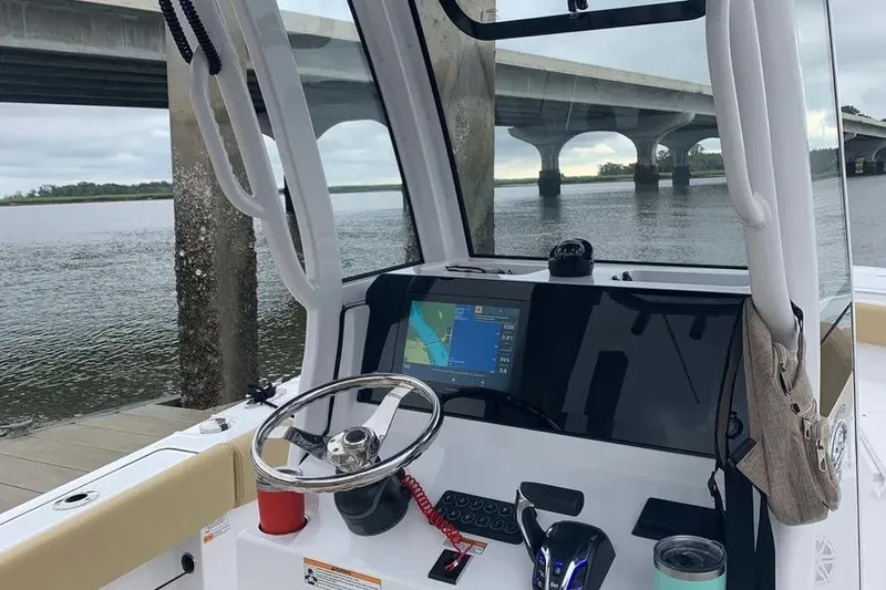 Slide: The Image of 2025 Sportsman Heritage 231 Center Console boat interior with navigation system, docked near a bridge. - 9