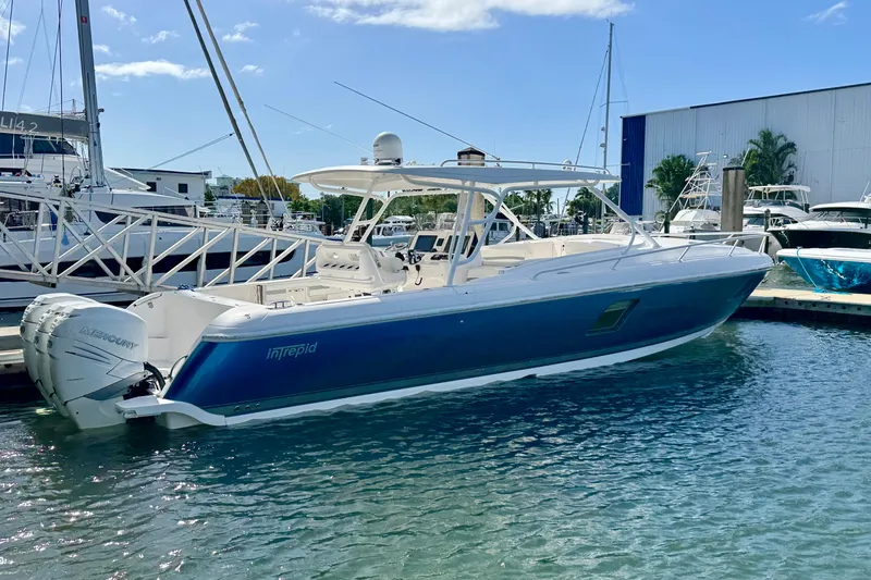 The Image of 2019 Intrepid 407 Cuddy boat docked at marina, featuring sleek blue design and powerful engines. - 0
