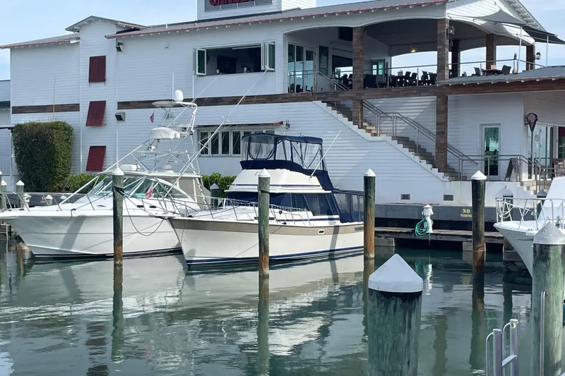 Slide: The Image of 1983 Bayliner 3270 Explorer docked at marina near waterfront building. - 1