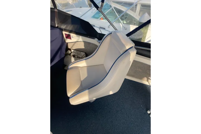 Slide: The Image of Captain's chair on 1983 Bayliner 3270 Explorer boat, featuring white upholstery and blue trim. - 11