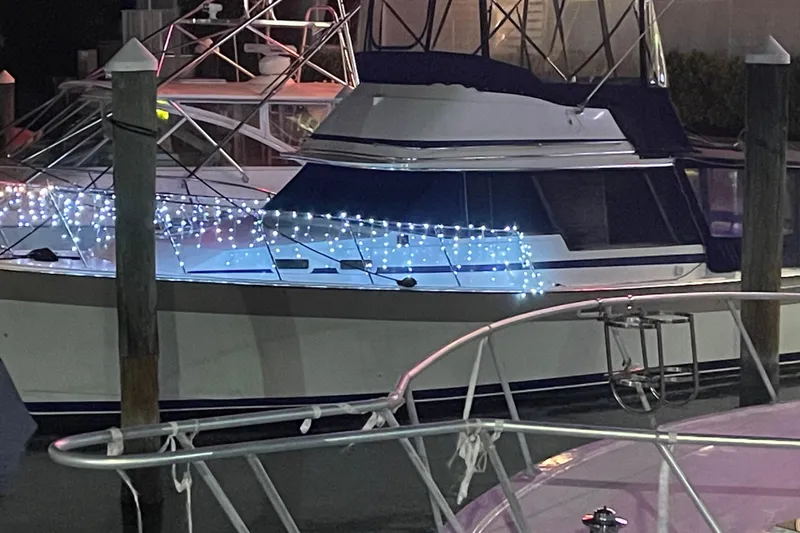 Slide: The Image of 1983 Bayliner 3270 Explorer with festive lights docked at night. - 2