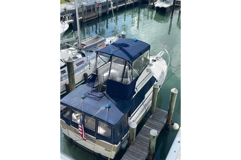 Slide: The Image of 1983 Bayliner 3270 Explorer docked at marina with blue canopy. - 3