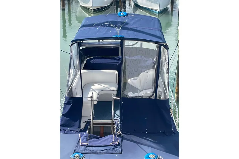 Slide: The Image of 1983 Bayliner 3270 Explorer with blue canopy and seating, docked in marina. - 5