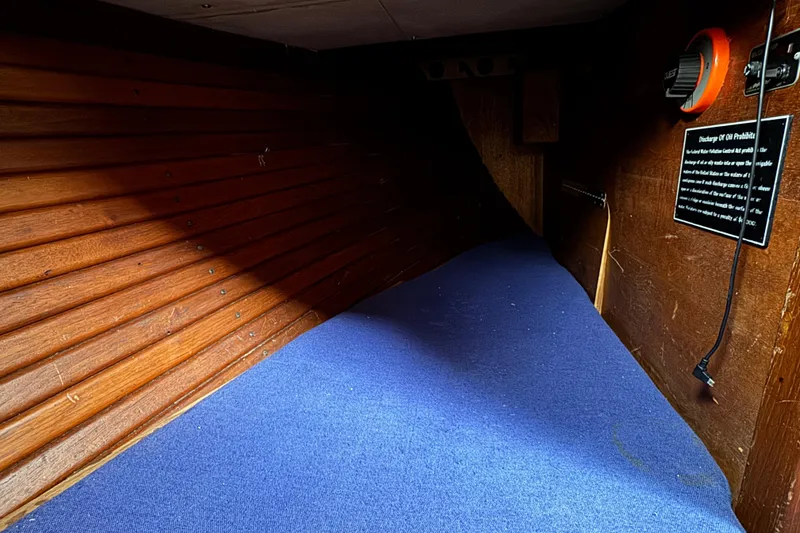 Slide: The Image of Interior of 1977 Westsail Cutter with wooden paneling and blue carpet flooring. - 15