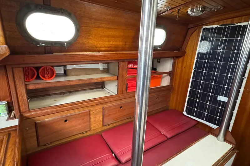Slide: The Image of 1977 Westsail Cutter interior with wooden cabinetry, red cushions, and solar panel. - 16