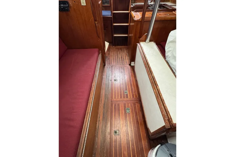 Slide: The Image of 1977 Westsail Cutter interior with wooden flooring and red seating. - 18