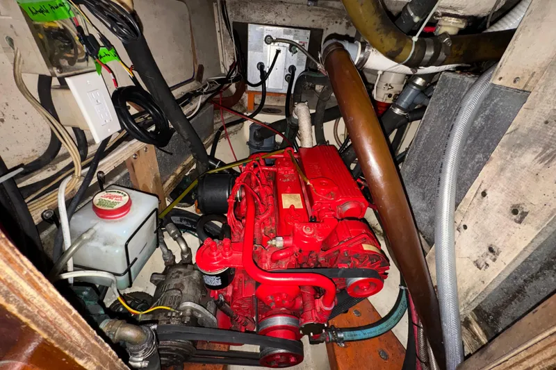 Slide: The Image of Engine compartment of a 1977 Westsail Cutter, featuring a red engine and various cables. - 21