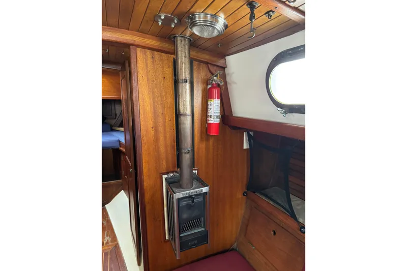 Slide: The Image of 1977 Westsail Cutter interior with wood paneling, stove, and fire extinguisher. - 23