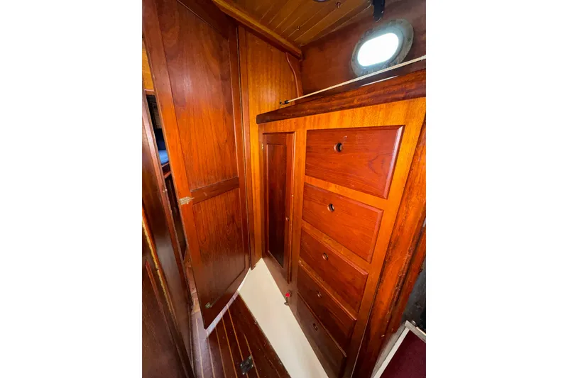 Slide: The Image of 1977 Westsail Cutter interior with wooden cabinetry and porthole window. - 26