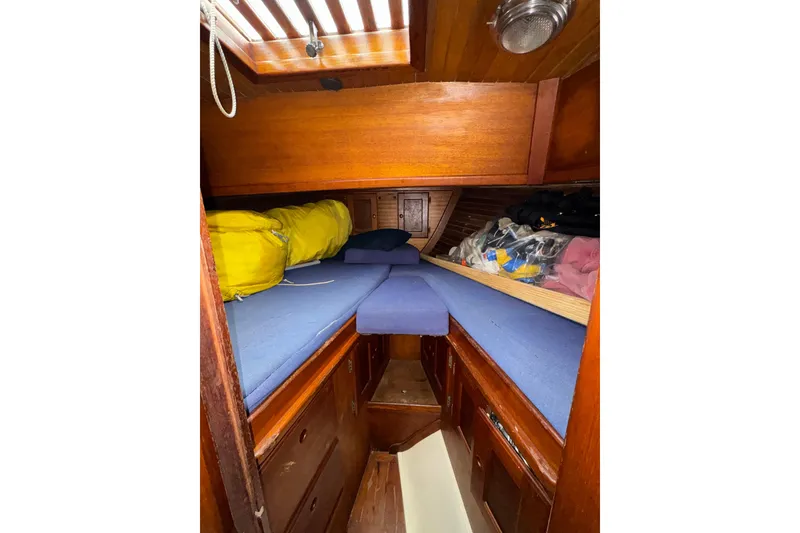 Slide: The Image of 1977 Westsail Cutter cabin interior with wooden finish and blue cushions. - 28
