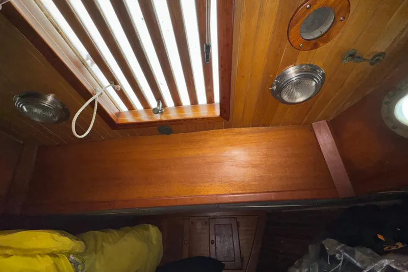 Slide: The Image of Interior of 1977 Westsail Cutter with wooden paneling and porthole. - 30