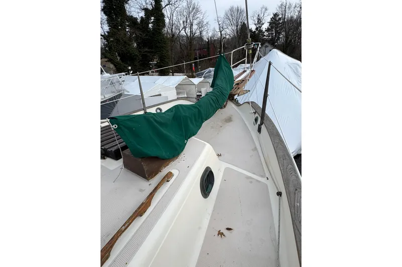 Slide: The Image of 1977 Westsail Cutter sailboat deck with green cover, docked outdoors. - 38