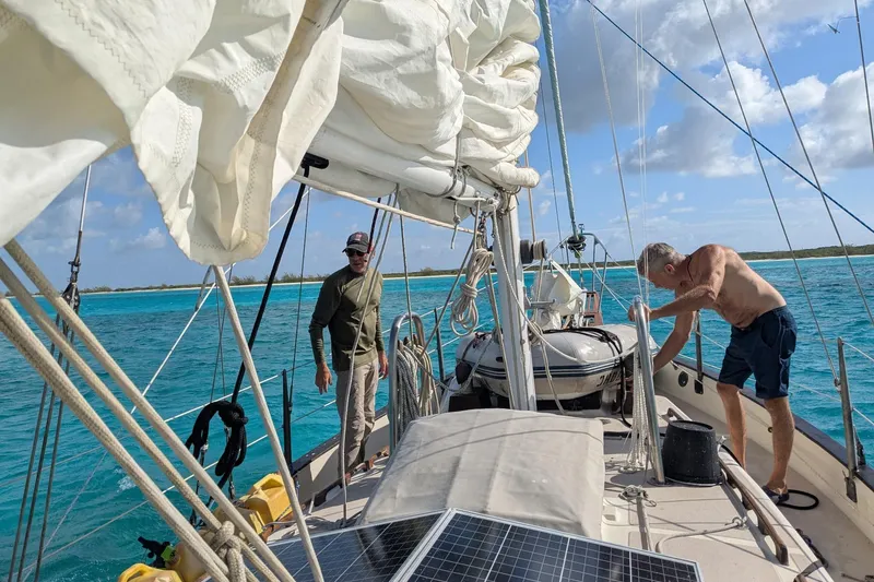 Slide: The Image of Two people on a 1977 Westsail Cutter sailboat in clear blue waters. - 44