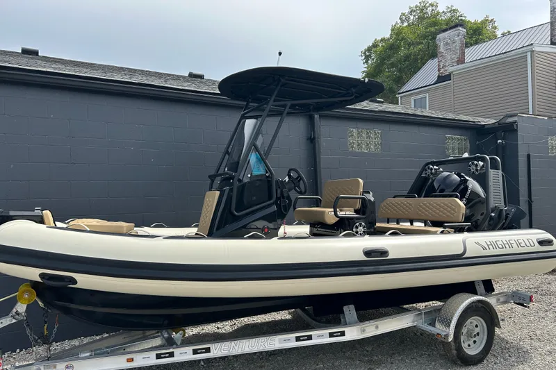 The Image of 2024 Highfield Sport 560 boat on trailer, parked outdoors near a gray building. - 0