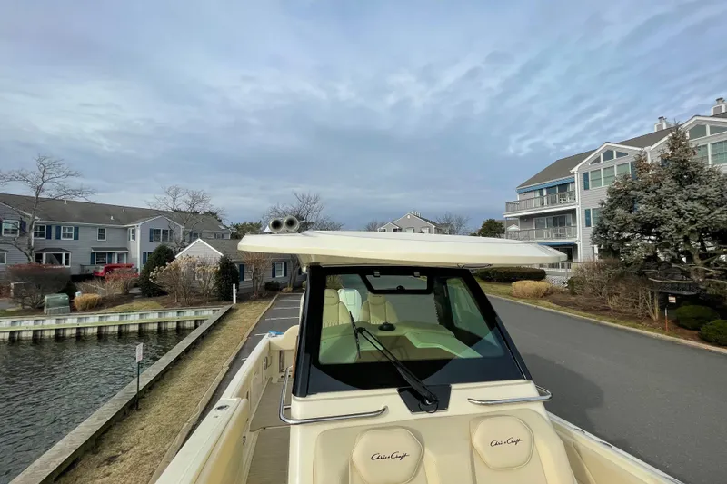 Slide: The Image of 2026 Chris-Craft 310 Catalina boat docked near waterfront homes under a cloudy sky. - 57