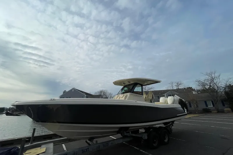 Slide: The Image of 2026 Chris-Craft 310 Catalina boat on trailer, parked near waterfront homes under cloudy sky. - 7