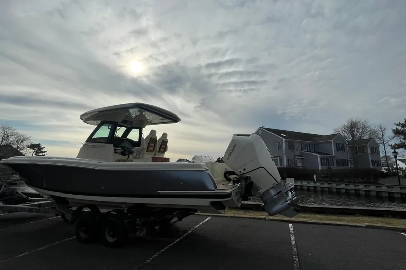 Slide: The Image of 2026 Chris-Craft 310 Catalina boat on trailer, parked near waterfront homes under cloudy sky. - 9