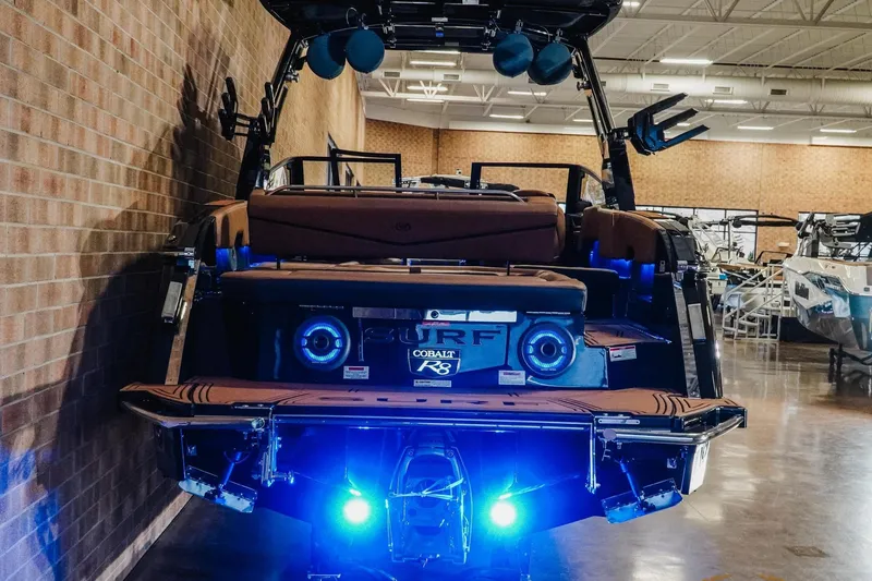 Slide: The Image of 2026 Cobalt R8 Surf boat with illuminated rear, showcased indoors. - 6