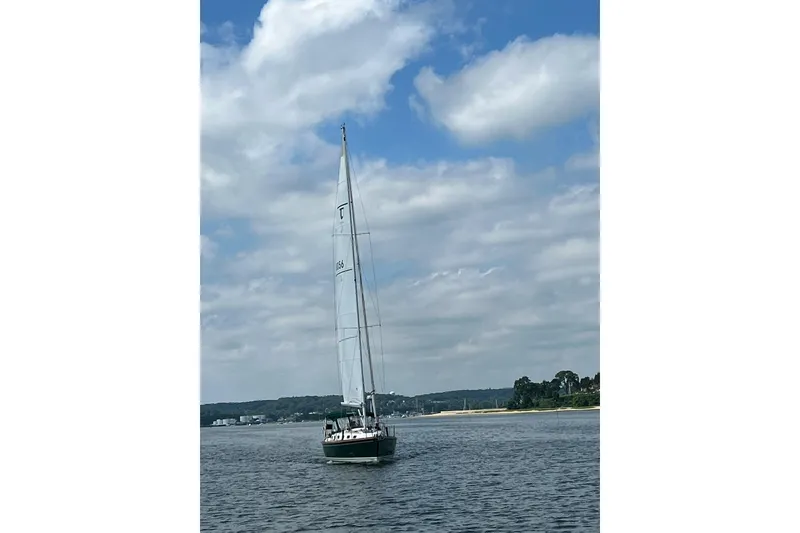 Slide: The Image of Sailboat Tartan 4100 (2001) cruising on a calm lake under a partly cloudy sky. - 4