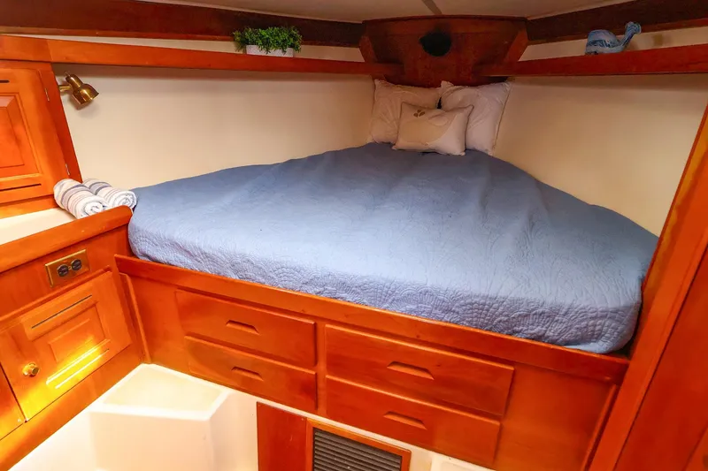 Slide: The Image of Cozy cabin interior of 2001 Tartan 4100 sailboat with wooden storage and blue bedding. - 48