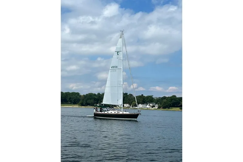 Slide: The Image of Sailboat Tartan 4100, 2001 model, cruising on a calm lake under a partly cloudy sky. - 5
