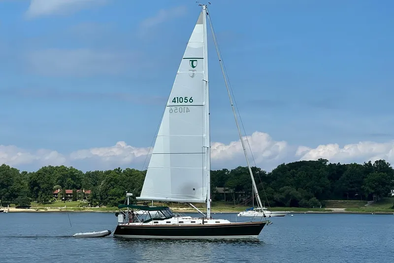 Slide: The Image of Sailboat Tartan 4100 from 2001 on a calm lake with lush green shoreline. - 6