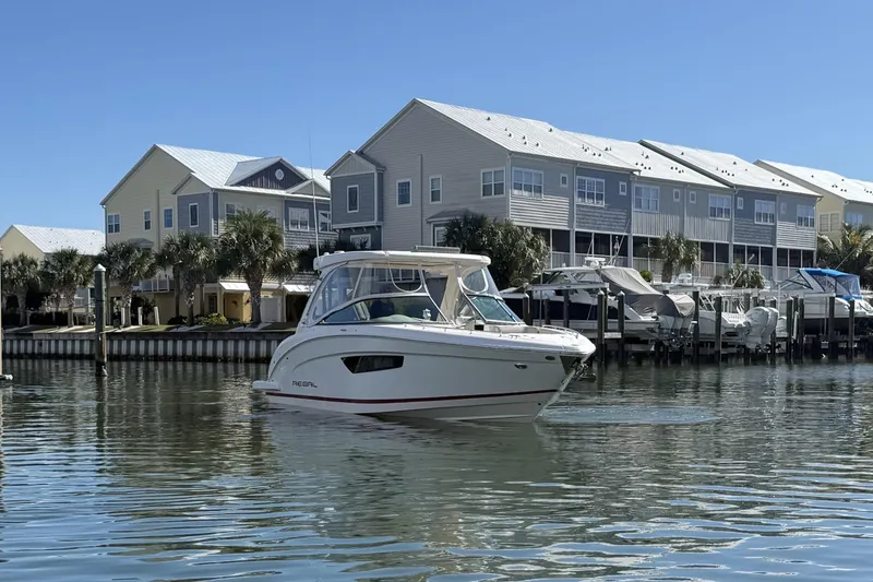 Slide: The Image of 2018 Regal 33 OBX boat on calm water near waterfront homes. - 2