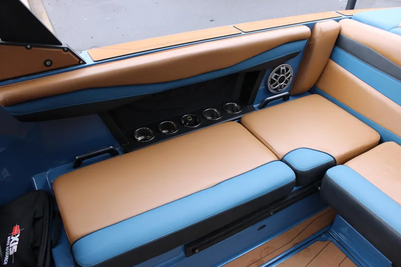 Slide: The Image of 2023 Axis A225 boat interior with tan and blue seating, cup holders, and speaker. - 10