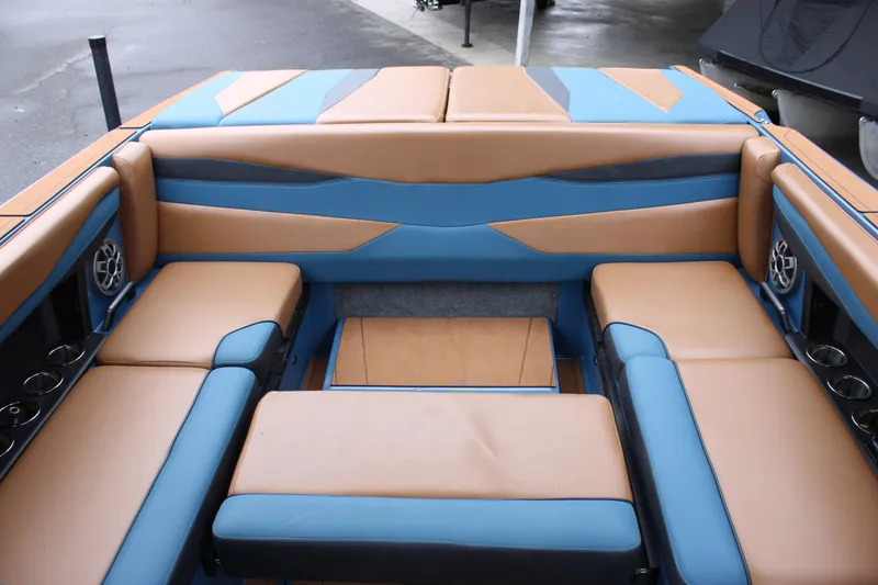 Slide: The Image of 2023 Axis A225 boat interior with tan and blue seating, cup holders, and speakers. - 15