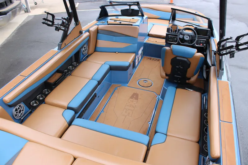 Slide: The Image of 2023 Axis A225 boat interior with tan and blue seating, modern dashboard, and cup holders. - 2