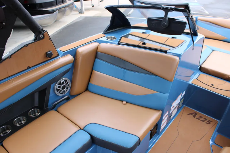 Slide: The Image of 2023 Axis A225 boat interior with tan and blue seating, featuring cup holders and speaker. - 3