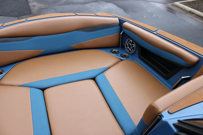 Slide: The Image of 2023 Axis A225 boat interior with tan and blue upholstery, featuring cup holders and speaker. - 6