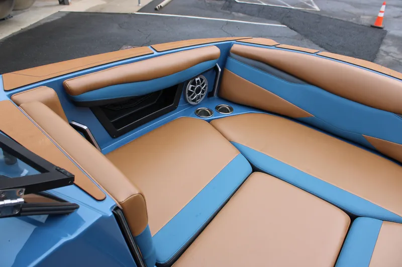 Slide: The Image of 2023 Axis A225 boat interior with tan and blue seating, cup holders, and speaker. - 7