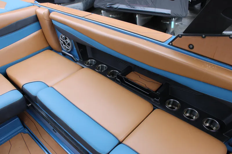 Slide: The Image of 2023 Axis A225 boat interior with tan and blue seating, cup holders, and speaker. - 9