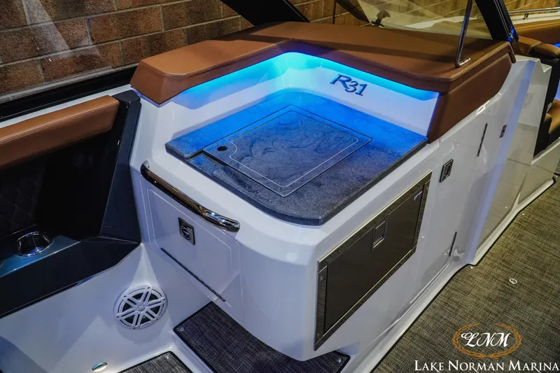 Slide: The Image of 2026 Cobalt R31 boat interior with blue LED lighting and brown seating at Lake Norman Marina. - 24