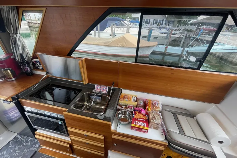 Slide: The Image of 2022 Cutwater C-30 Sedan interior kitchen with stove, sink, and snacks by window. - 37