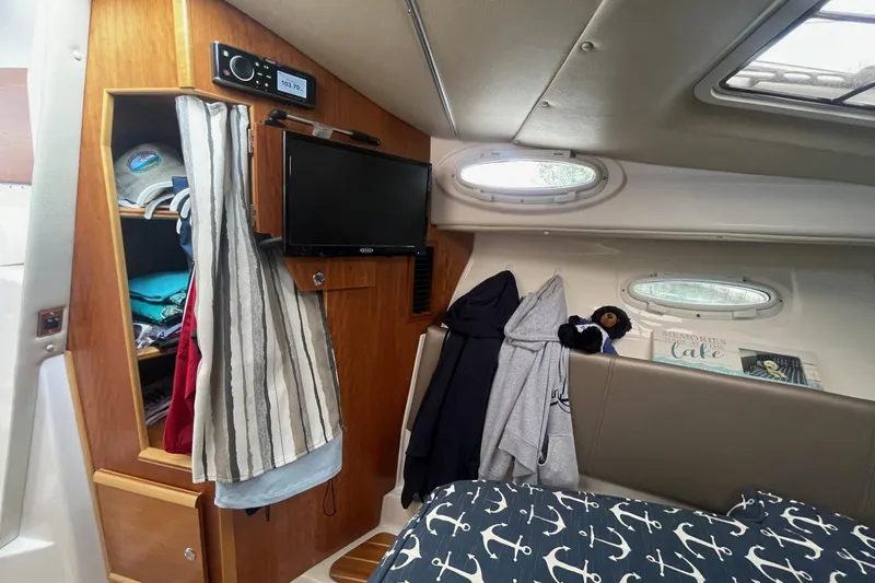 Slide: The Image of 2022 Cutwater C-30 Sedan interior with TV, storage, and nautical-themed bedding. - 42