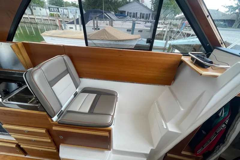 Slide: The Image of 2022 Cutwater C-30 Sedan interior with seating, wooden cabinetry, and marina view. - 48