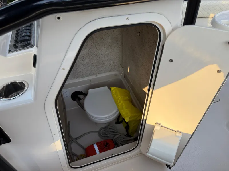 Slide: The Image of 2021 Carolina Skiff 23 Ultra Elite boat storage compartment with marine toilet and safety equipment. - 11