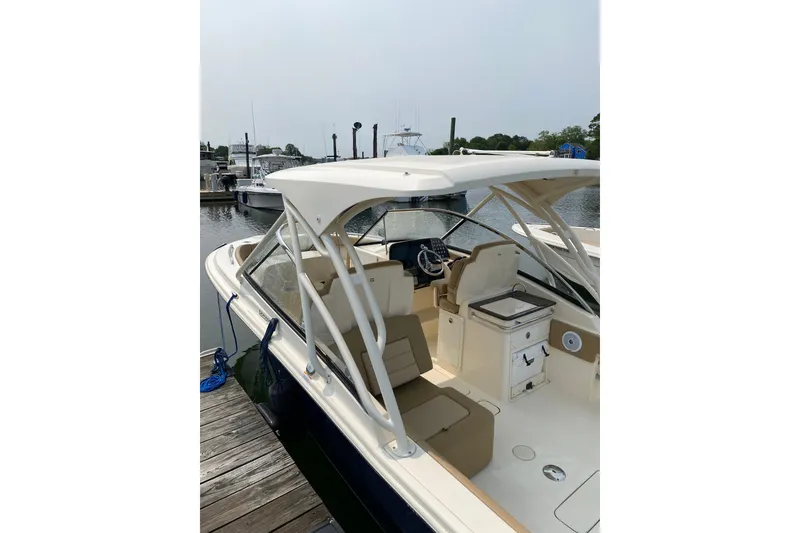 Slide: The Image of 2019 Scout 255 Dorado boat docked at marina, featuring spacious seating and helm. - 4