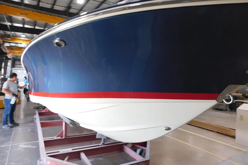 Slide: The Image of 2025 Chris-Craft Launch 27 boat in a workshop, blue hull with red stripe. - 3