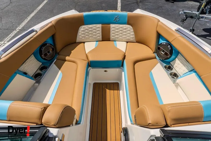 Slide: The Image of 2022 MasterCraft X24 boat interior with tan and blue seating, featuring cup holders and speakers. - 14