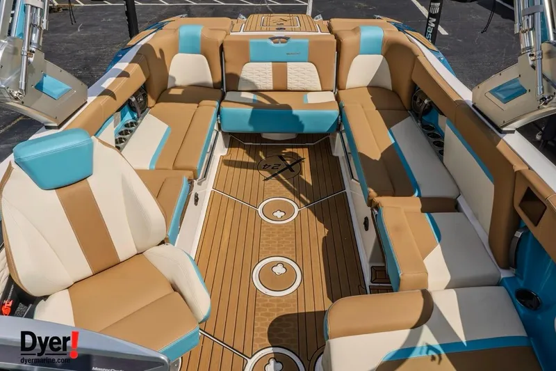 Slide: The Image of 2022 MasterCraft X24 boat interior with tan and blue seating, teak flooring. - 15