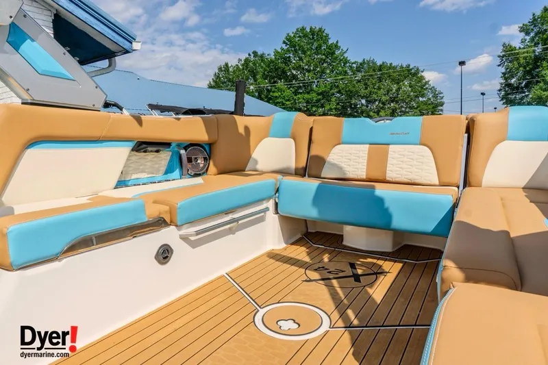 Slide: The Image of 2022 MasterCraft X24 boat interior with tan and blue seating, teak flooring, and clear sky. - 16
