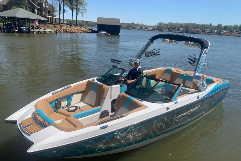 Slide: The Image of 2022 MasterCraft X24 boat on a lake with a person at the helm. - 2