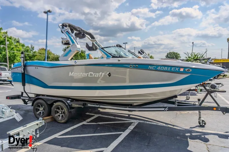 Slide: The Image of 2022 MasterCraft X24 boat on trailer in parking lot, under a partly cloudy sky. - 9