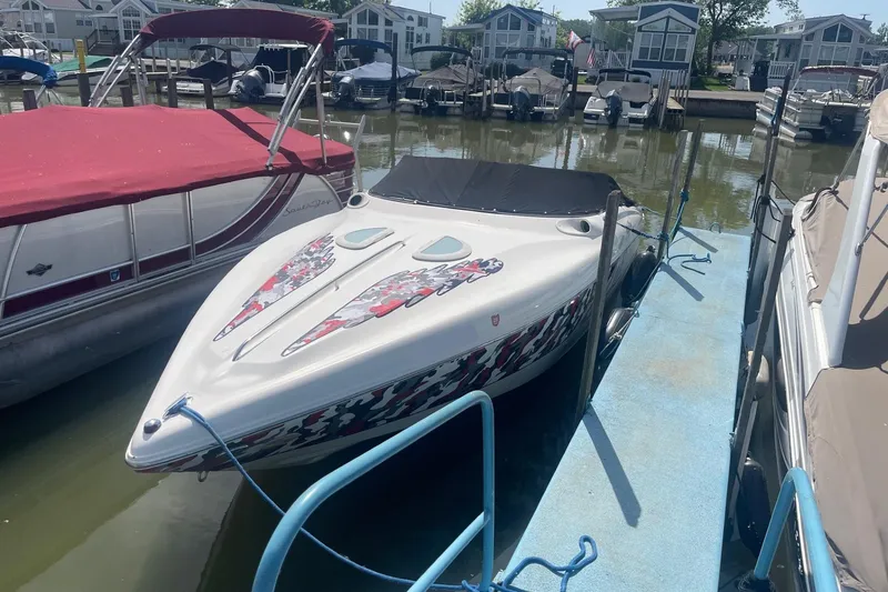 Slide: The Image of 2001 Rinker 262 Captiva boat docked, featuring colorful graphics and black cover. - 2