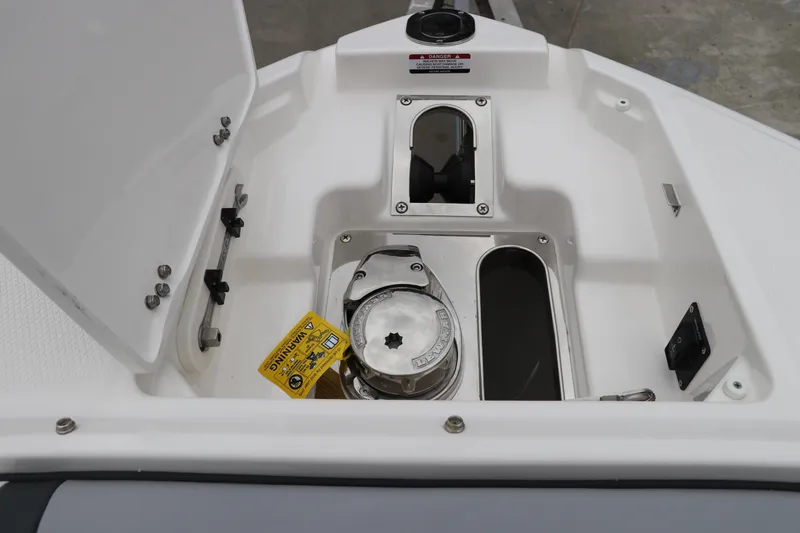Slide: The Image of 2026 Chaparral 270 OSX boat anchor compartment with open hatch and warning label. - 53