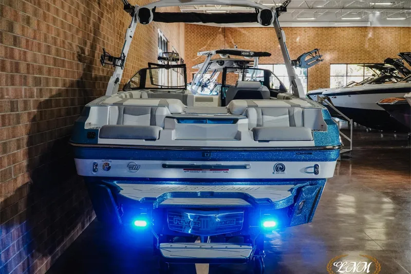 Slide: The Image of 2026 Malibu Wakesetter 22 MXZ boat with blue LED lights in showroom. - 10