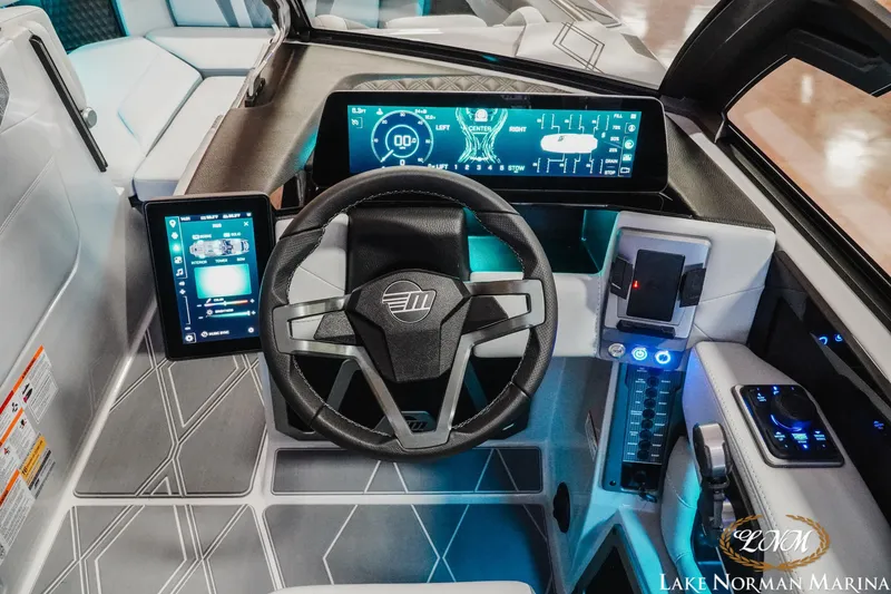 Slide: The Image of 2026 Malibu M230 boat dashboard with advanced digital displays and modern steering wheel. - 13
